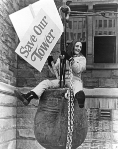 Mary Stiles Kimmell sitting on wrecking ball holding "Save Our Tower" sign
